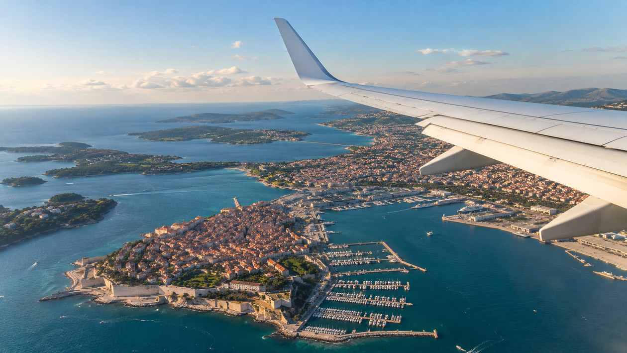 Uçak penceresinden beyaz kanat ve aşağıda kıyı şehri